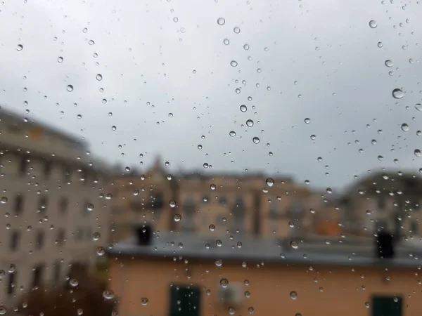 Genova, Italy - 11/28/2019: An amazing caption of the waterdrop over the window after very strong rain with an incredible coloured sky and a piece of sunshine. Macro photography of the drop.