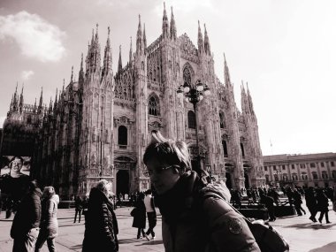 Milan, İtalya - 12 / 25 / 2019: Milano Duomo 'sunun kış günlerindeki muhteşem bir manşeti, bazı insanların akşamın tadını çıkardığı, güzel siyah beyaz arka plan ve bazı ufuk çizgilerinin güzel fotoğrafı