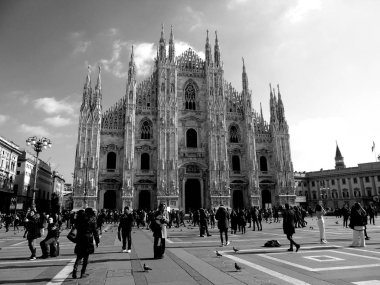 Milan, İtalya - 12 / 25 / 2019: Milano Duomo 'sunun kış günlerindeki muhteşem bir manşeti, bazı insanların akşamın tadını çıkardığı, güzel siyah beyaz arka plan ve bazı ufuk çizgilerinin güzel fotoğrafı