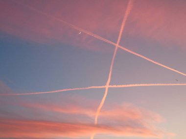 Cenova, İtalya - 01 / 25 / 2020: Genova şehrinin üzerinde kış günbatımının muhteşem bir manşeti, güzel kızıl gökyüzü, bazı inanılmaz bulutlar ve arka planda küçük ay ışığı.