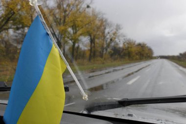 Arabanın ön camında Ukrayna bayrağı asılıdır. Sonbahar yağmuru..