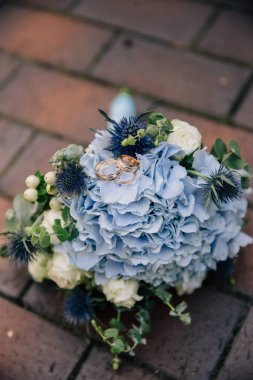 Mavi ortancalı bir düğün buketinde yüzük.