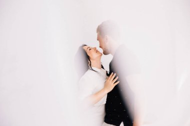 Beyaz tül boyunca öpüşen çifte odaklan.