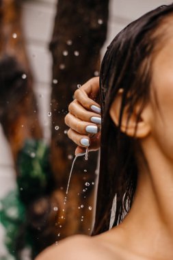 Bir kız bahçede yaz duşu aldığında parmaklarına damlayan damlalara odaklan.