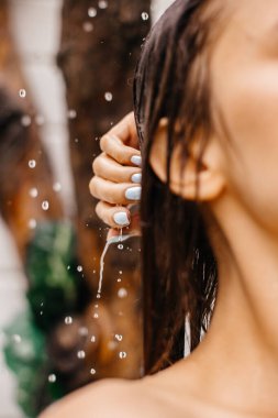 Bir kız bahçede yaz duşu aldığında parmaklarına damlayan damlalara odaklan.