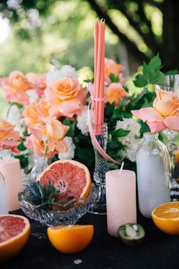 Düğün masasının dekorunda turunçgil meyveleri ve canlı mercan renklerinin karışımı.