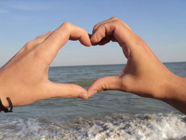 Love sea. Photo of two hands in heart shape at sea