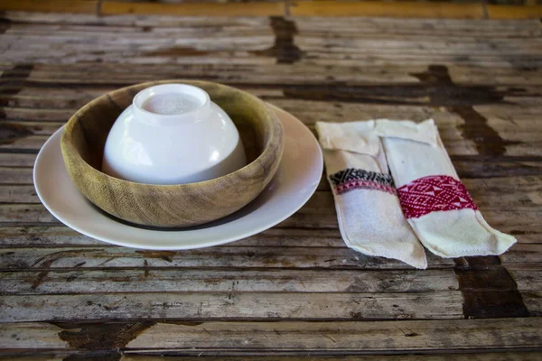 竹のテーブルの上に木製のボウルとスプーンの手 — ストック写真