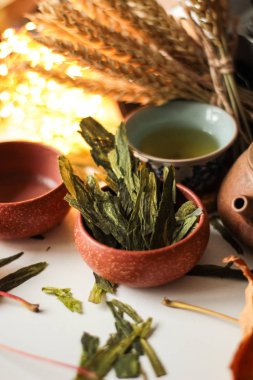 Natürmort bitki yaprakları ve yeşil çay ile kahverengi kase, arka plan buğday kulaklara ayarla çaydanlık