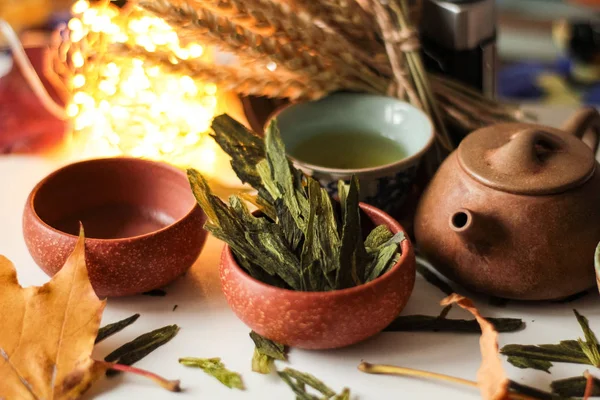 oryantal kil su ısıtıcısı ile bitkisel yaprakları ve yeşil çay küçük kase, tabloda demet buğday kulak arka plan üzerinde