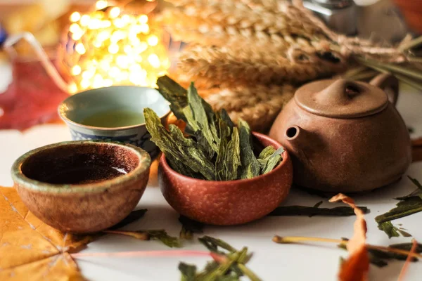 asian tea set with herbal leaves and bunch of wheat ears on background