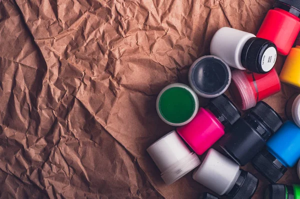 gouache paint bottles for textile on crumpled kraft paper surface