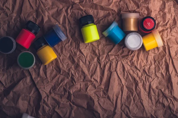 watercolor paint bottles for textile on crumpled kraft paper surface