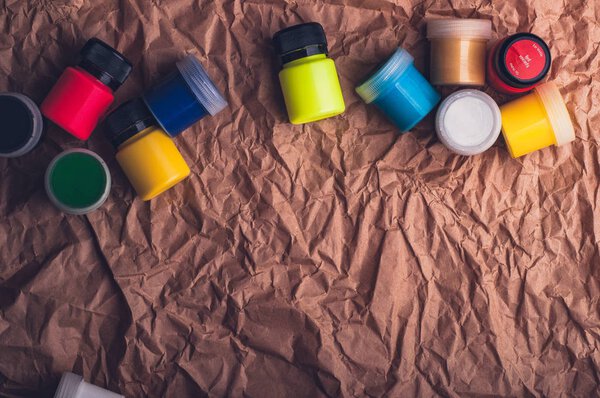 colorful watercolor paint bottles for textile on crumpled kraft paper surface