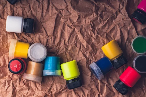 multicolored paint bottles for textile on crumpled kraft paper surface