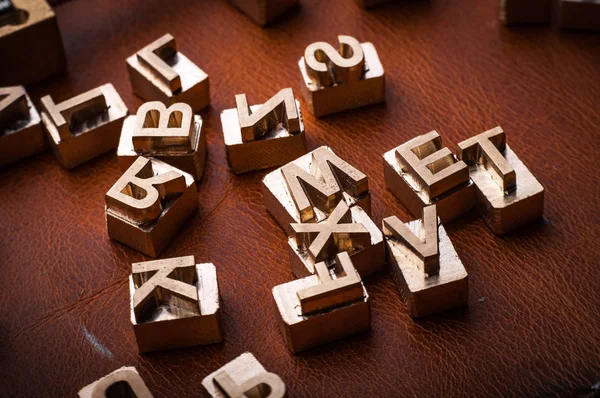 golden leather alphabet stamps on red surface