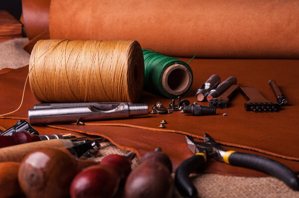 close up shot of sewing spools of threads and leather craft tools