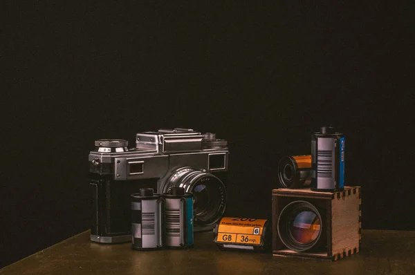 vintage camera and film rolls with wooden camera lens, studio shot