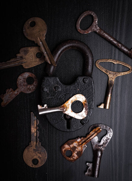 padlock and rusty keys on wooden surface 