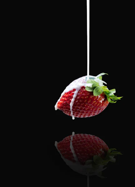 Beautiful side view of milk stream flowing to tasty strawberry w — Stock Photo, Image