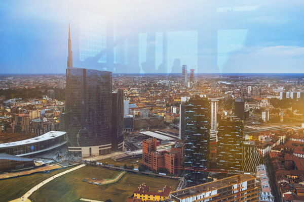 Beautiful multi colored toned aeroview image of Milan, Italian urban cityscape with skyscrapers and different buildings on the streets and background with the sunse