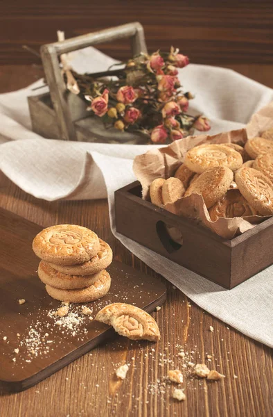 Suchých růží a kulaté sušenky na dřevěné prkno — Stock fotografie