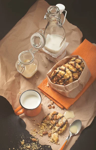 Peanut cookies, kopp mjölk, glas burkar på skrynkligt papper — Stockfoto