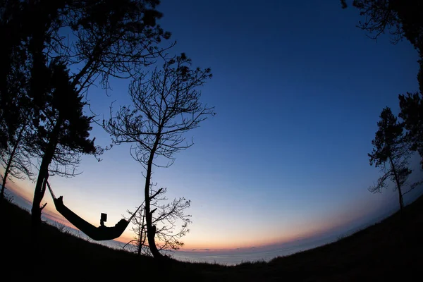Człowiek, czytanie w przyrodzie na hamaku w cieniu drzew z pięknym — Zdjęcie stockowe