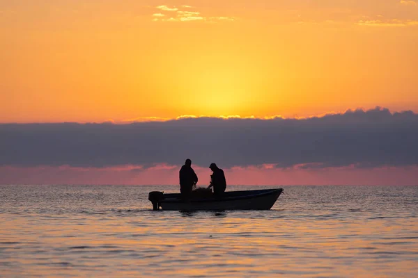 Two fishermen on a boat fishing on a sea with beautiful sunrise — Stock Photo, Image