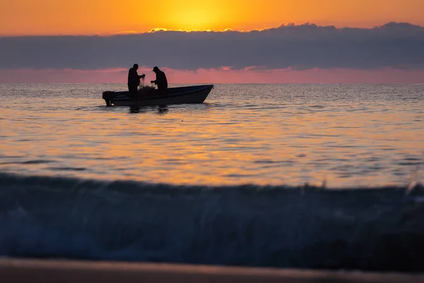 Due pescatori su una barca che pescano su un mare con bella alba — Foto Stock