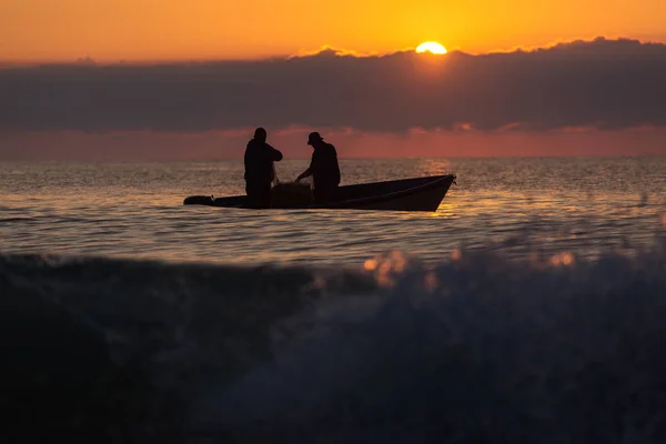 Dos pescadores en un barco pescando en un mar con hermoso amanecer —  Fotos de Stock