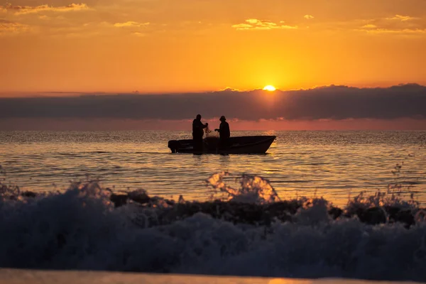 Due pescatori su una barca che pescano su un mare con bella alba — Foto Stock