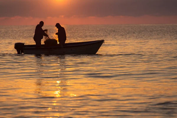 Två fiskare på en båt fiske på ett hav med vacker soluppgång — Stockfoto