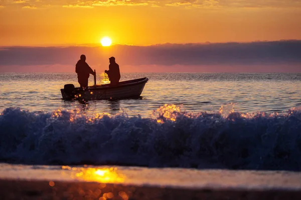 Due pescatori su una barca che pescano su un mare con bella alba — Foto Stock