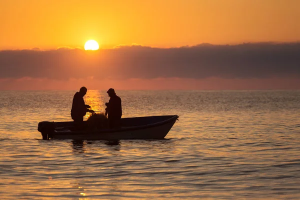 Dos pescadores en un barco pescando en un mar con hermoso amanecer —  Fotos de Stock