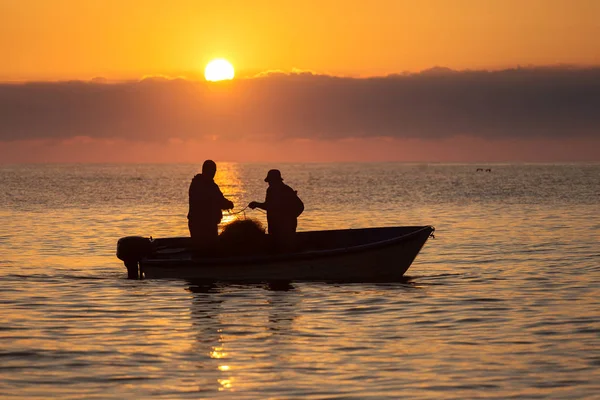 Dos pescadores en un barco pescando en un mar con hermoso amanecer —  Fotos de Stock