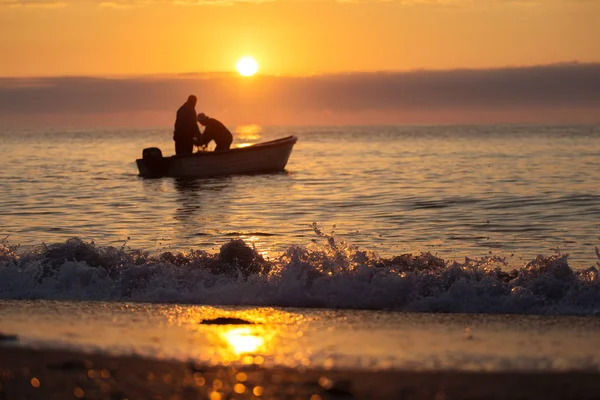 Deux pêcheurs sur un bateau pêchant sur une mer avec un beau lever de soleil — Photo