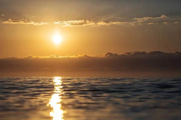 Lever de soleil sur une mer avec de petites vagues et de beaux nuages à l'arrière — Photo