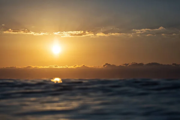 Lever de soleil sur une mer avec de petites vagues et de beaux nuages à l'arrière — Photo