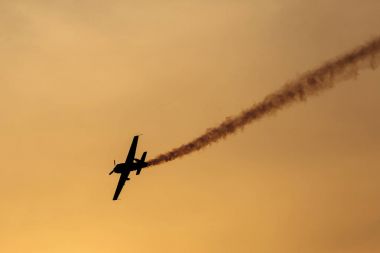 Günbatımı dumanlı arka planda uçakta silüeti