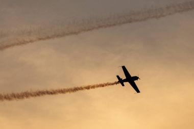 Günbatımı dumanlı arka planda uçakta silüeti