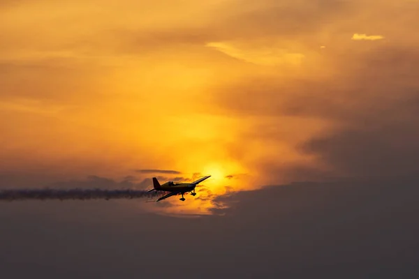 Силует літака на заході сонця з димом на фоні — стокове фото