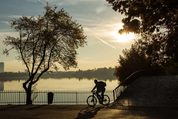 Muž se na kole v parku za úsvitu s krásné podzimní barvy a — Stock fotografie