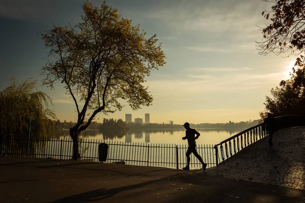 Homem correndo em um parque ao nascer do sol com belas cores de outono e — Fotografia de Stock
