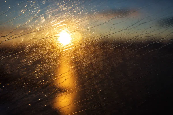 Arka planda günbatımı olan bir uçağın camına su damlaları. — Stok fotoğraf