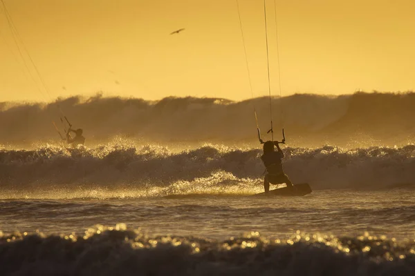 Silhoutte de kitesurfistas disfrutando de grandes olas al atardecer en Essaoui — Foto de Stock