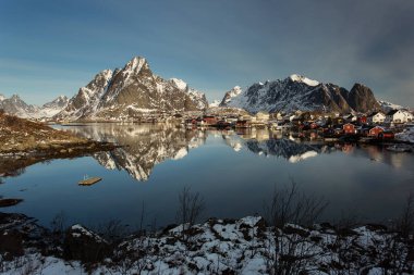 Kışın güzel Sacrisoya köyü manzarası. Arka planda gündoğumuyla birlikte anıtlar. Lofoten, Norveç.
