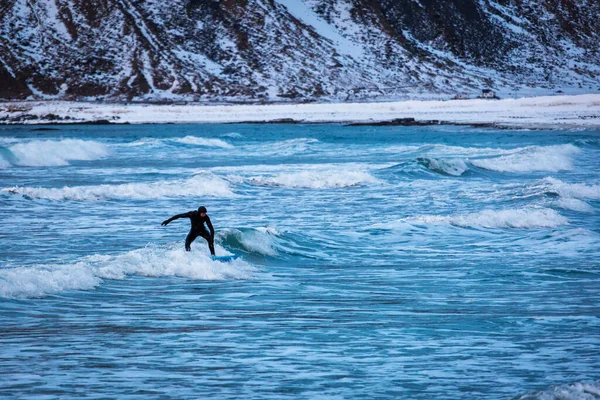 山を背景に冬の時間に波の上にサーファー — ストック写真