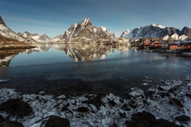 Kışın güzel Sacrisoya köyü manzarası. Arka planda gündoğumuyla birlikte anıtlar. Lofoten, Norveç.