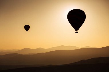 Arka planda gündoğumu olan balonların silueti, hava manzarası